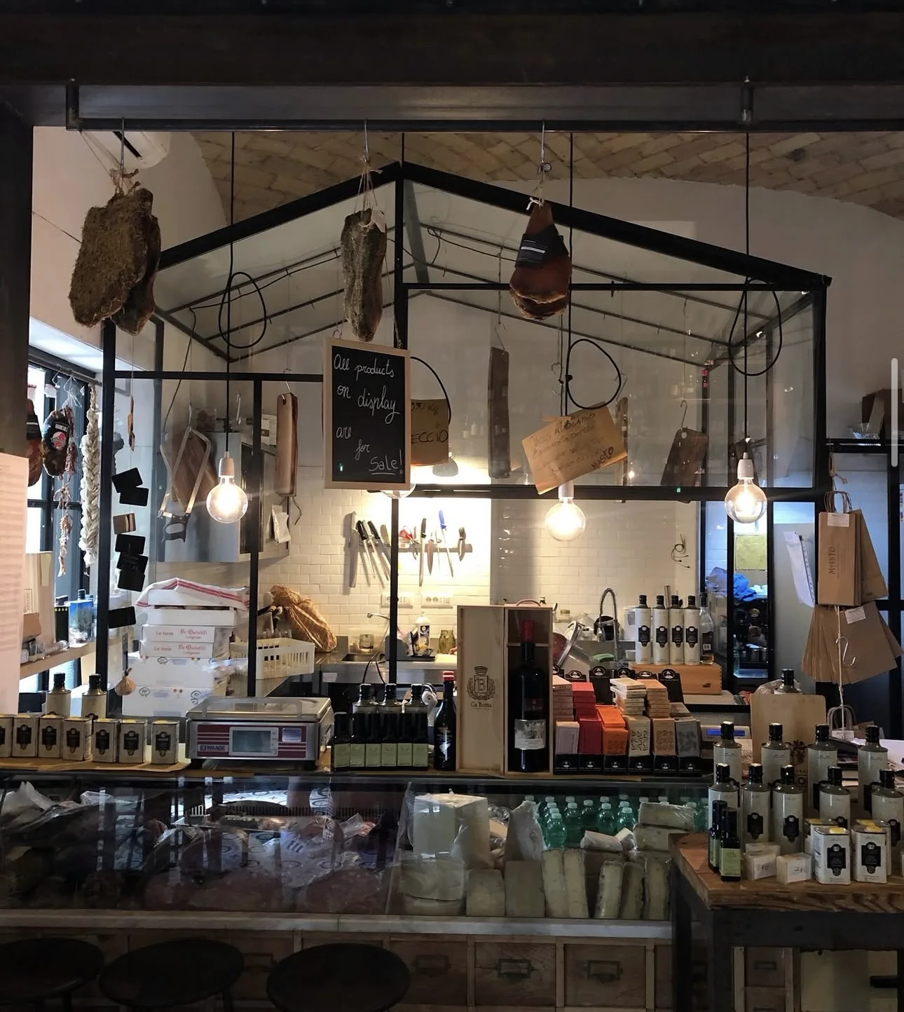 Il banco della salumeria di MASTO: salumi appesi, oli e formaggi sul marmo
