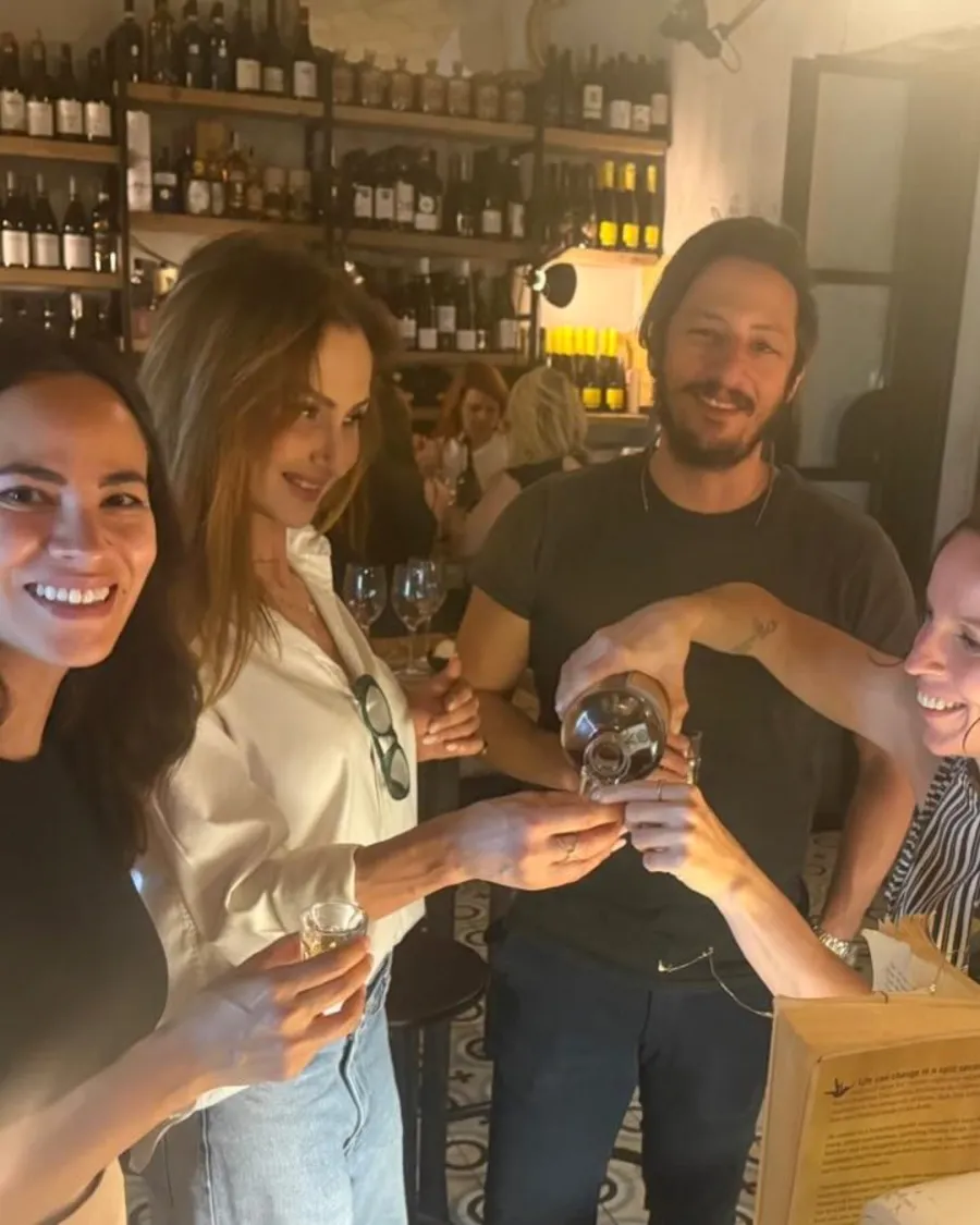 Un gruppo di ospiti brinda davanti alla parete dei vini di MASTO