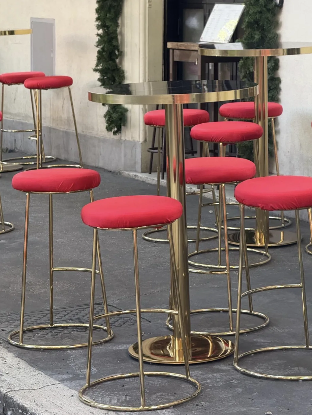 Sgabelli di velluto rosso e tavolini in ottone del dehors