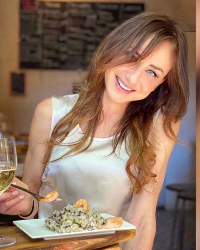 Rita al banco di MASTO, con un calice di bianco e un piatto di risotto